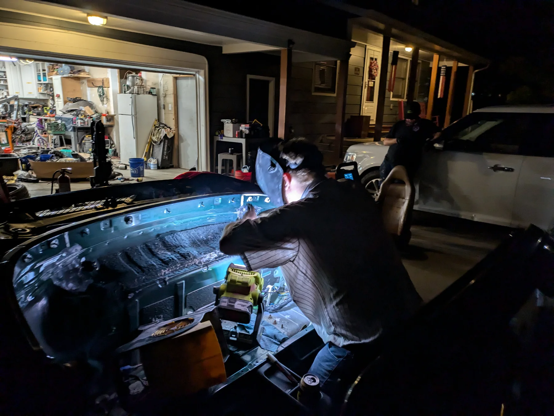Nighttime fabrication work on a race car in the driveway
