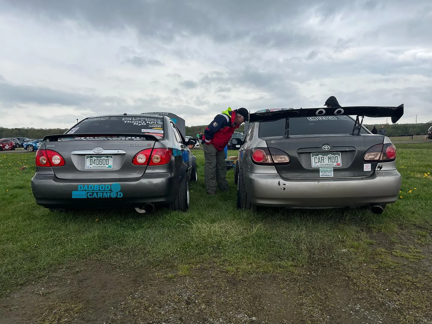 Two gray Dadbod Carmod Corollas parked together on grass