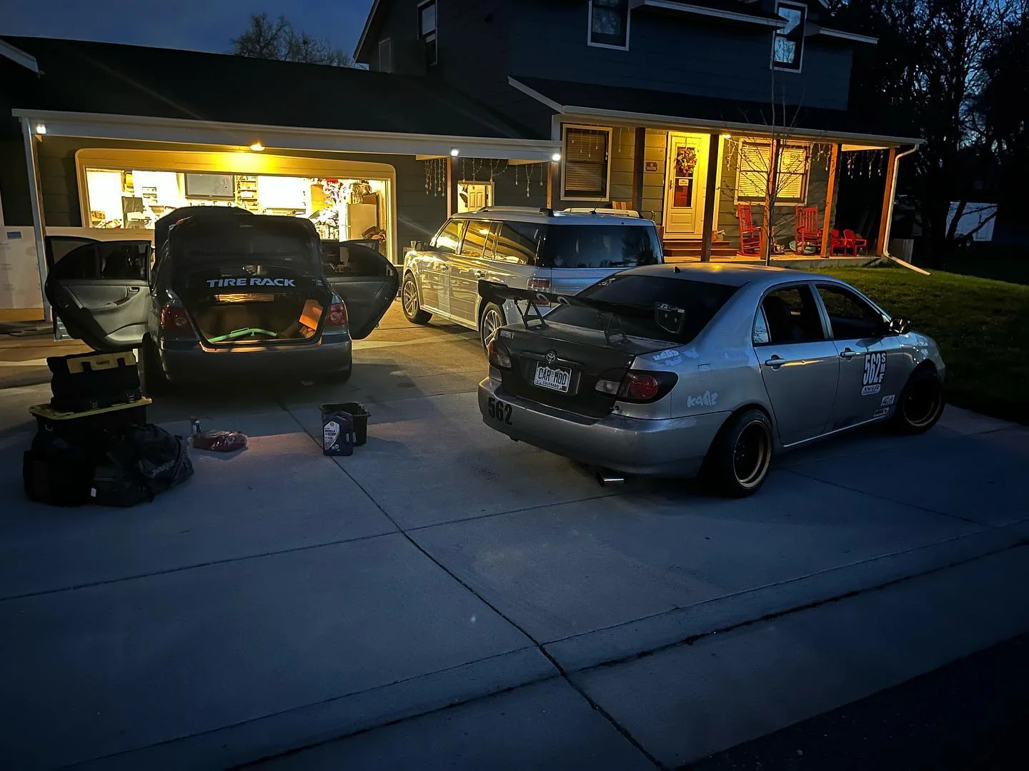 Two gray Dadbod Carmod Corollas parked outside a lit garage at night
